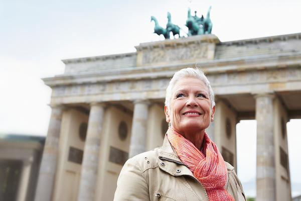 Ältere Frau lächelt vor dem Brandenburger Tor