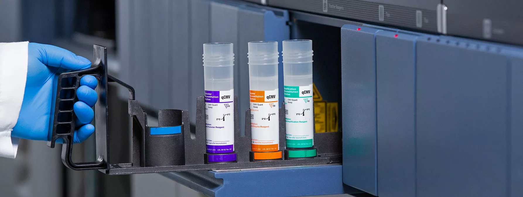 Gloved hand putting test tubes into equipment