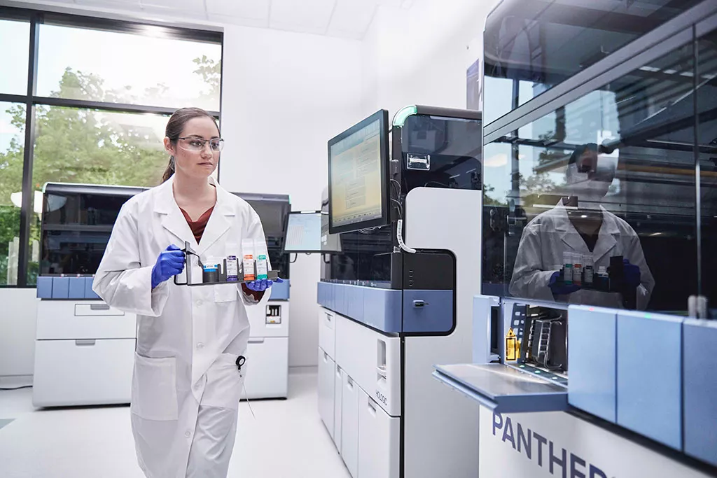 Labortechniker mit Proben-Tray zum Einlegen in das Panther System
