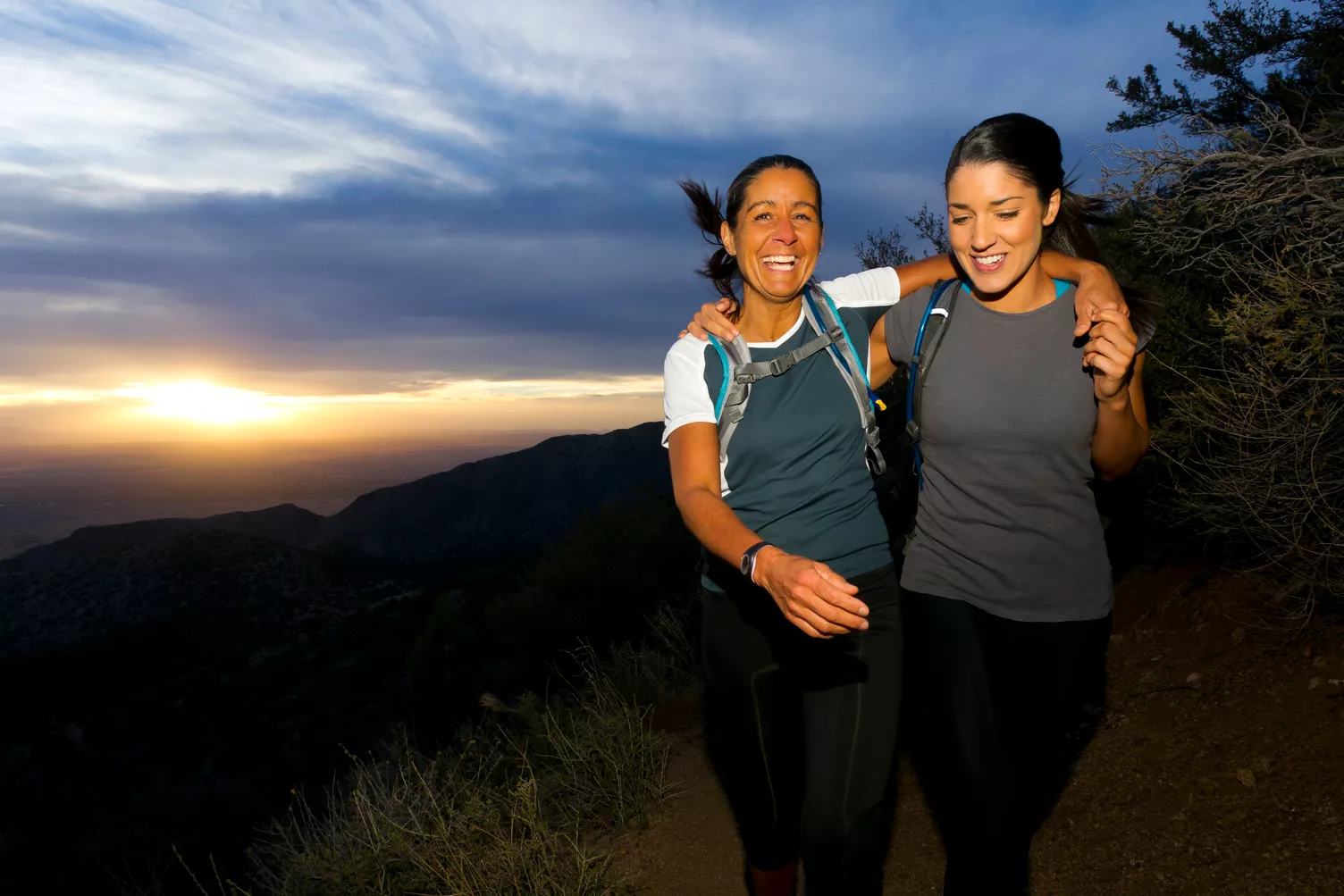 Zwei Frauen auf einem Wanderweg bei Sonnenuntergang.