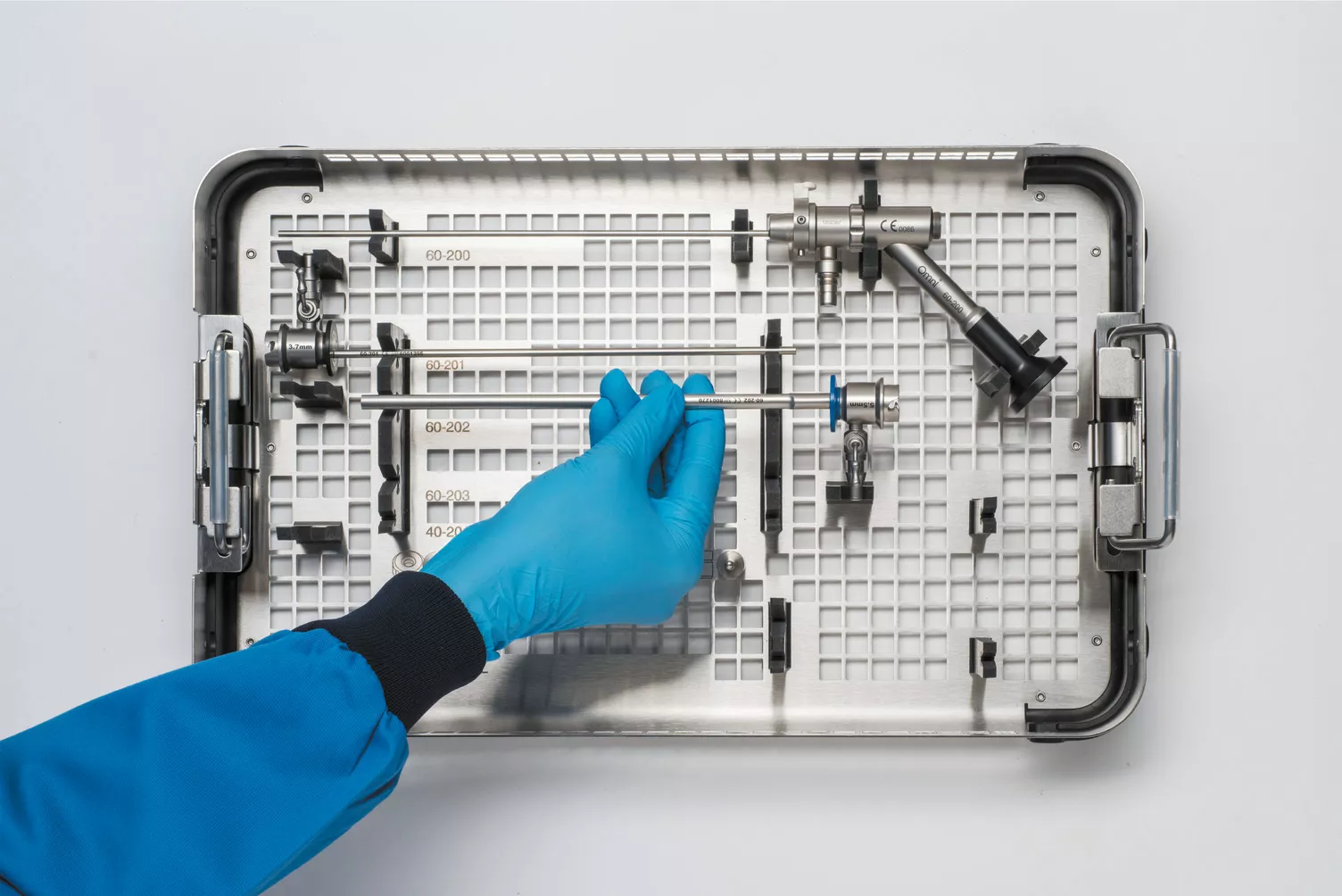 Behandschuhte Hand bei der Arbeit mit Instrumenten-Tray am Tisch.