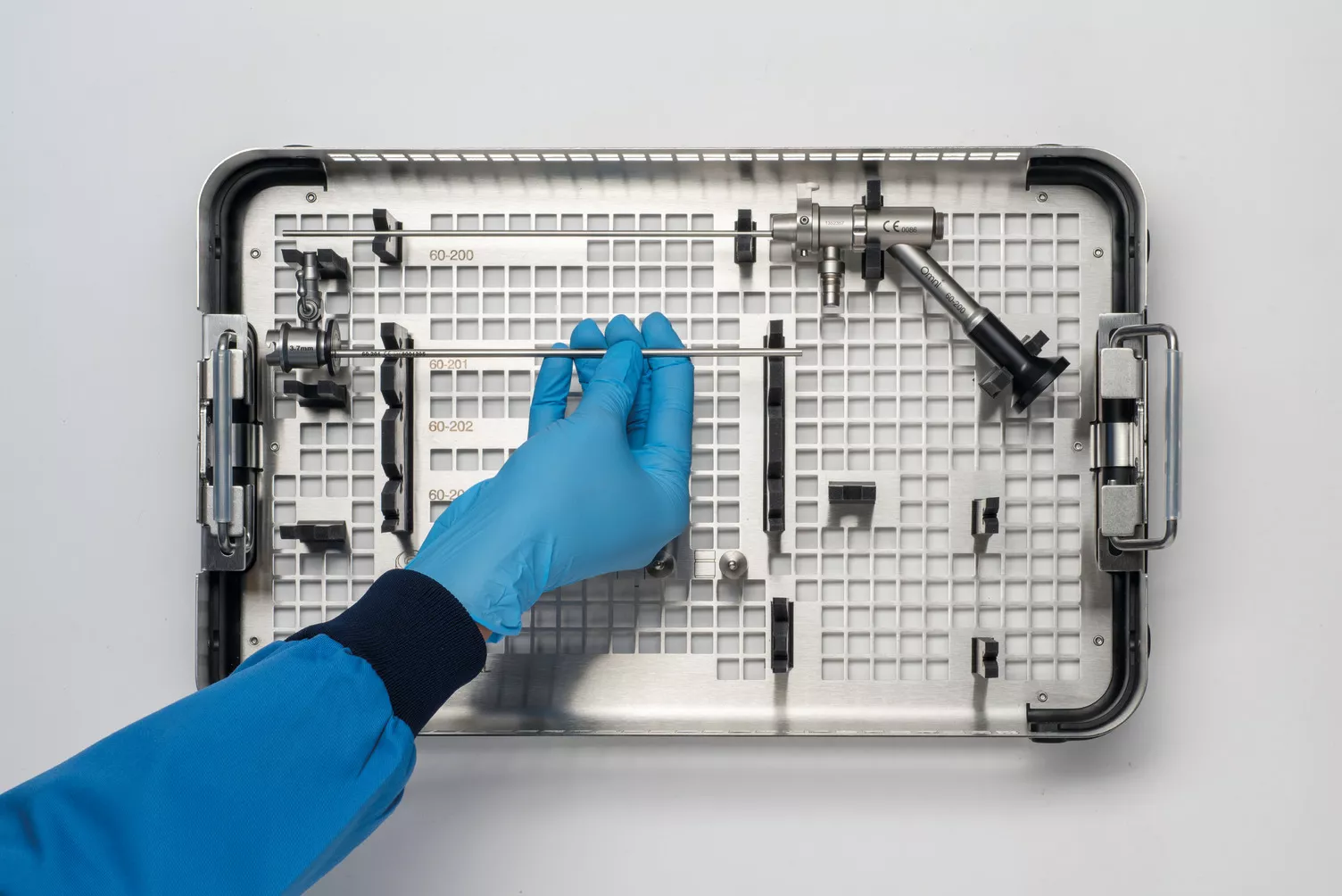 Behandschuhte Hand bei der Arbeit mit Instrumenten-Tray am Tisch.