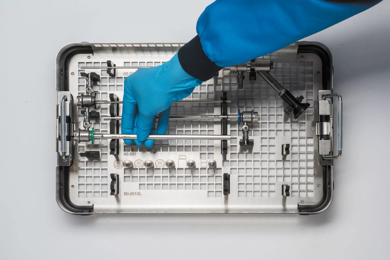 Behandschuhte Hand bei der Arbeit mit Instrumenten-Tray am Tisch.