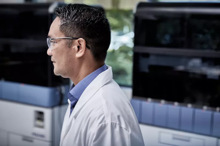 Seitenansicht eines Labortechnikers in Laborumgebung mit medizinischen Laborsystemen